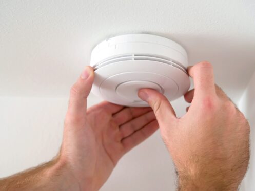 A man testing a carbon monoxide detector on the wall.